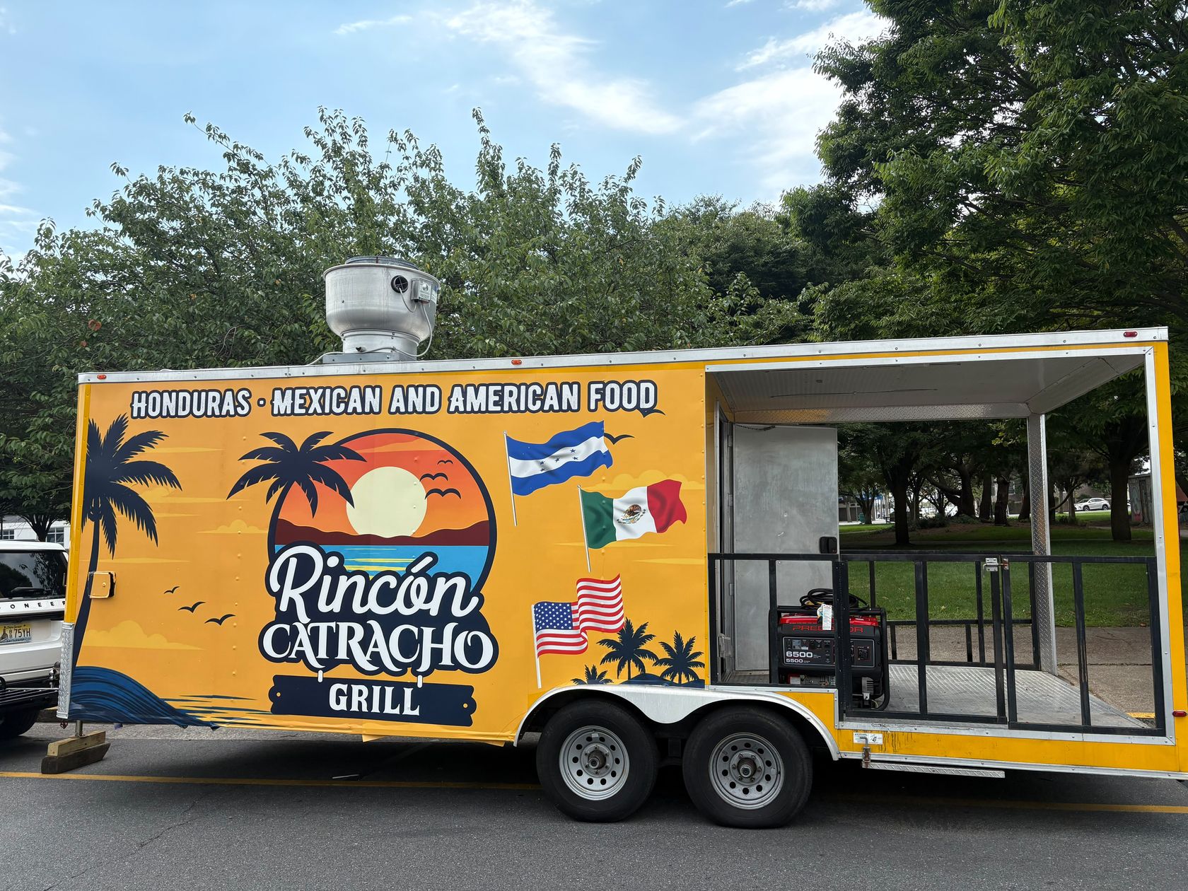 Food truck de Rincón Catracho Grill, remolque amarillo con el logo del atardecer y banderas de Honduras, México y Estados Unidos